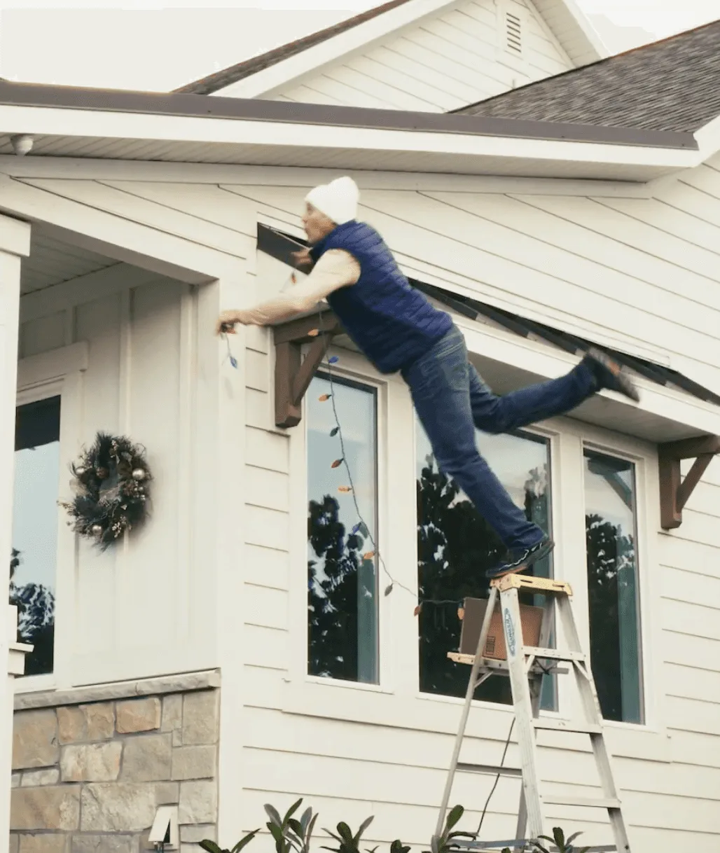 Person on a ladder hanging Christmas lights
